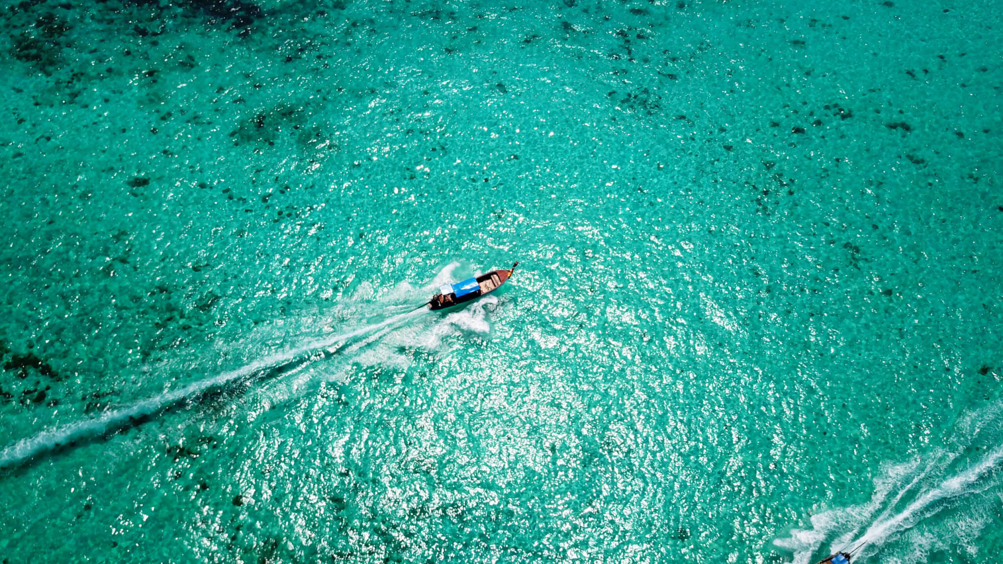 Small boat sailing through clear turquoise waters