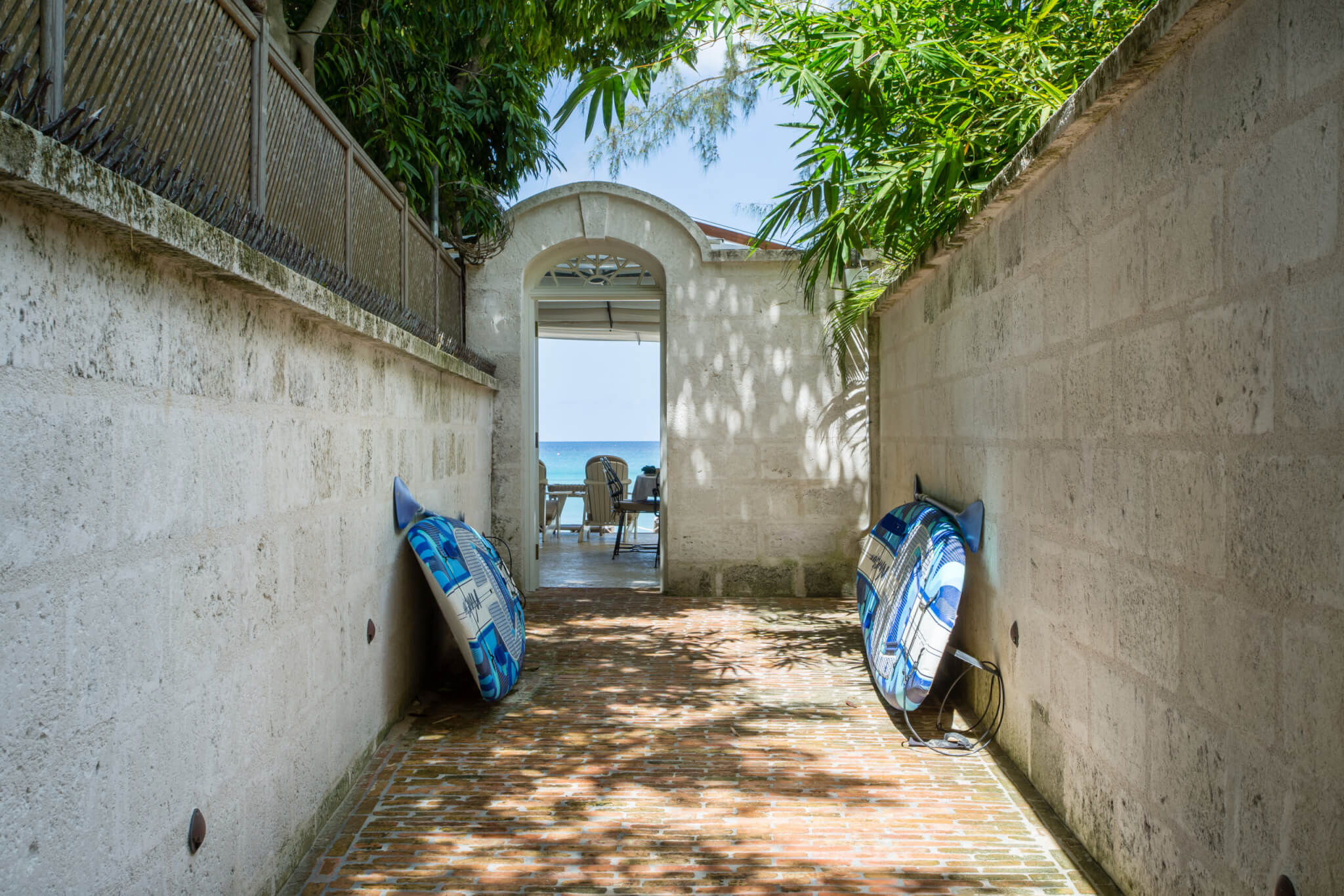 Alleyway leading to a beach with two paddle boards placed on either wall