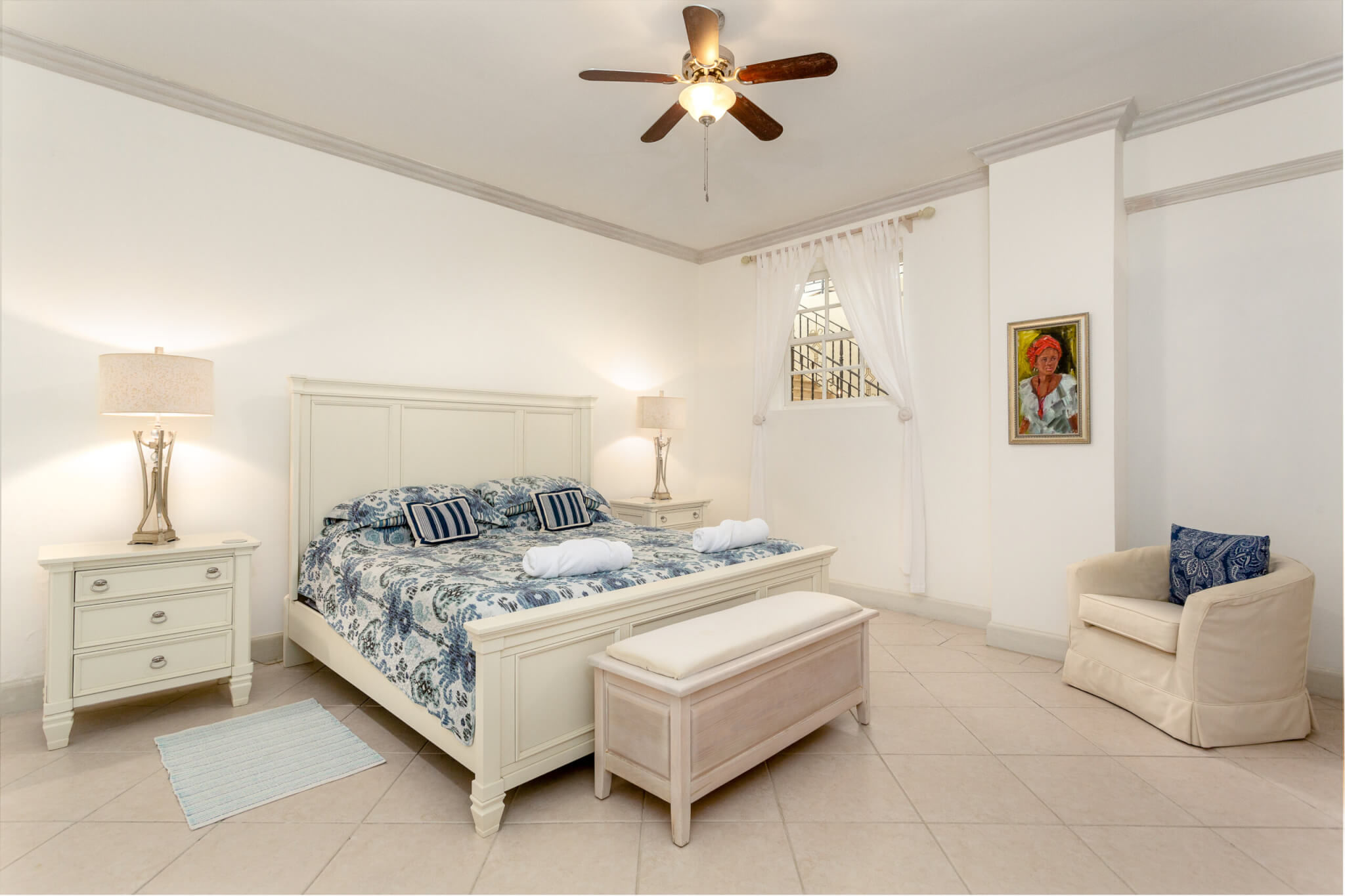 Bedroom with a large bed with blue patterned sheets and an arm chair to one side