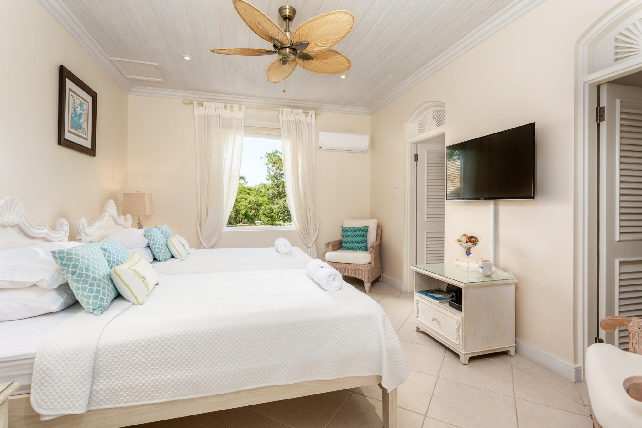 Bedroom with a fan over the bed and a flatscreen TV Hung on the wall to the foot of the bed