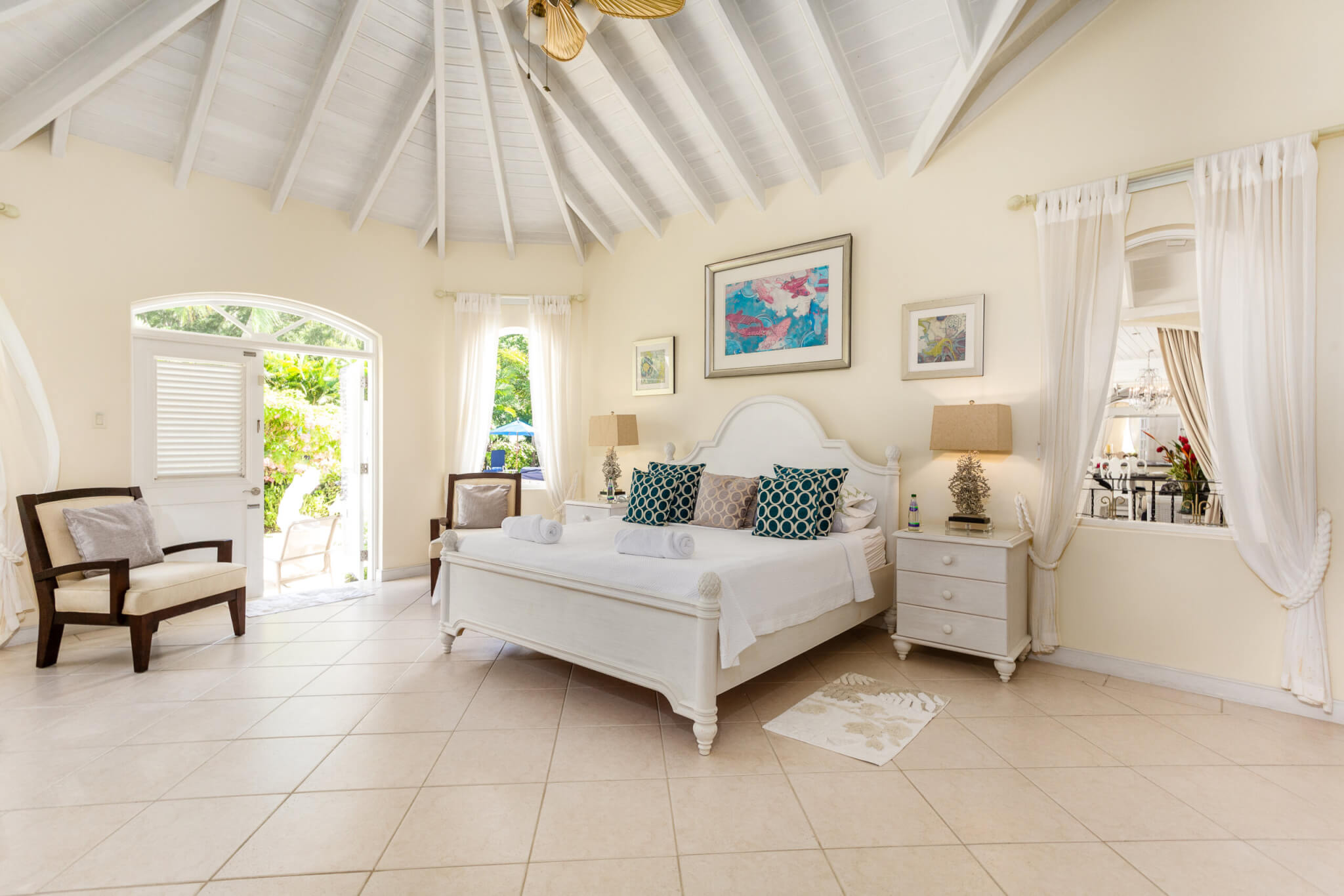 Bedroom with a large white bed, high ceilings and direct access to the garden