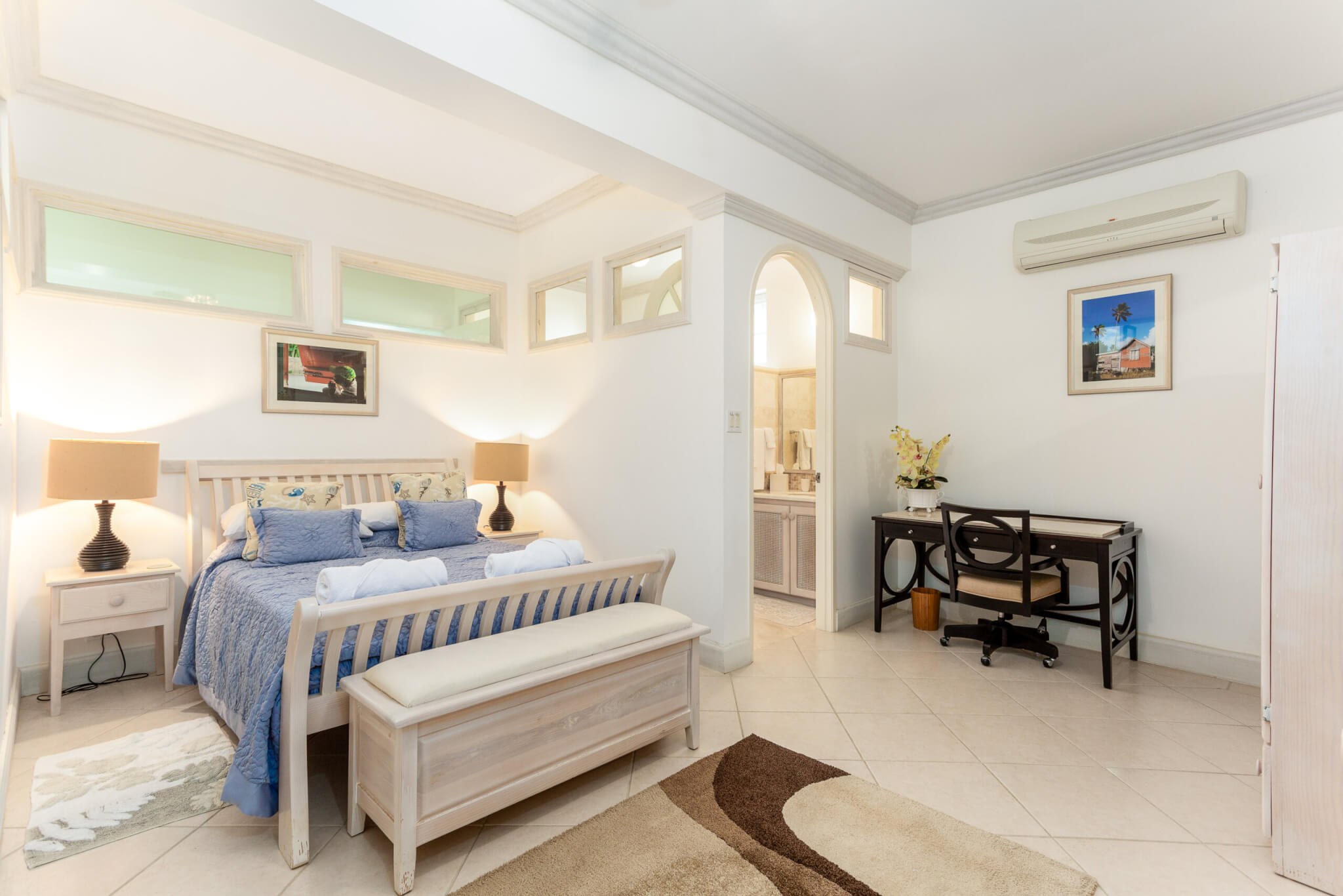 Bedroom with a king size bed with blue sheets and a rug at the end of the bed